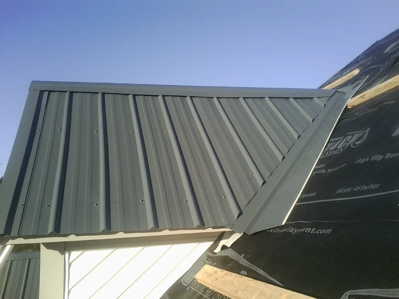 Gray metal roof panels going on over a garage gable in New Virginia