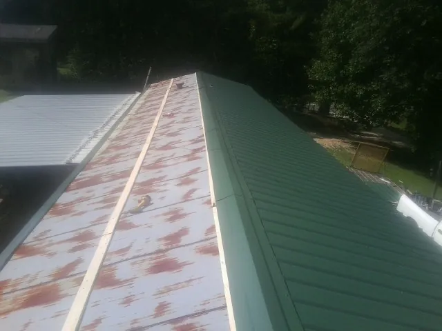 Old rusted panels beside newly installed green metal roofing — Wind Damage Roof Repair by Roofing Brothers in New Virginia