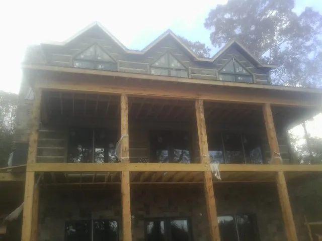 Dormers and porch framing on a large log home under construction — Roof Coating work by our crew in New Virginia