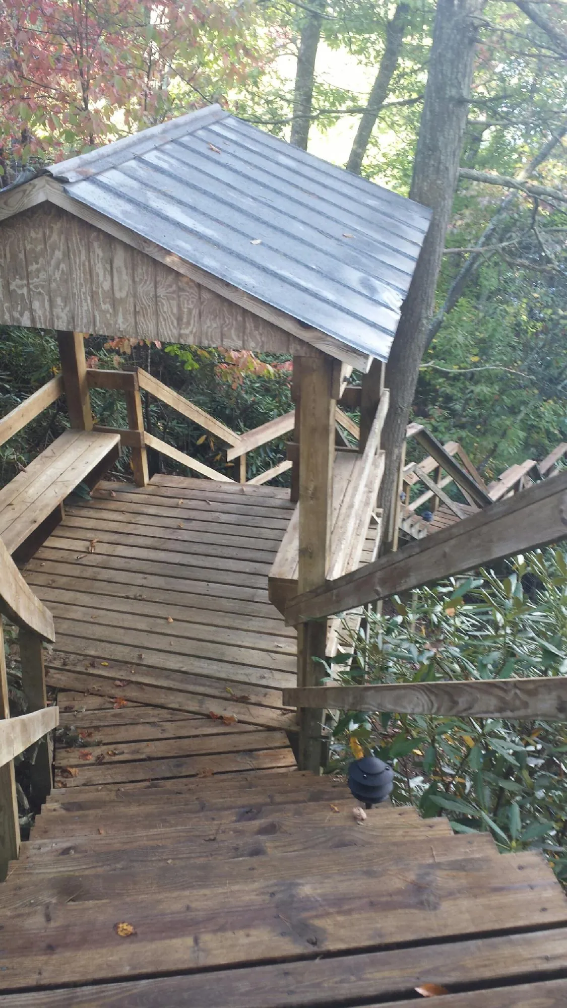 Metal roofed shelter over wooden steps on a wooded walkway — Skylight Repair & Installation work by our crew in New Virginia