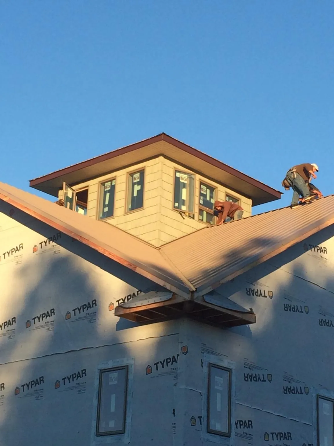 Roofers working around a rooftop cupola on a new metal roof at sunset — Roof Waterproofing in New Virginia by Roofing Brothers